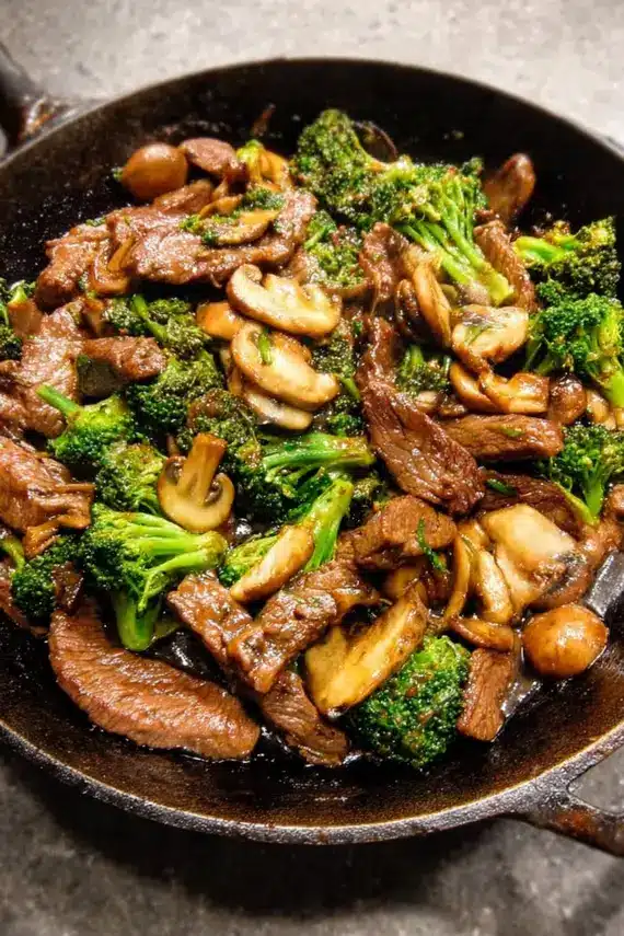 Finished beef broccoli mushroom stir fry served on a white plate with chopsticks and garnish