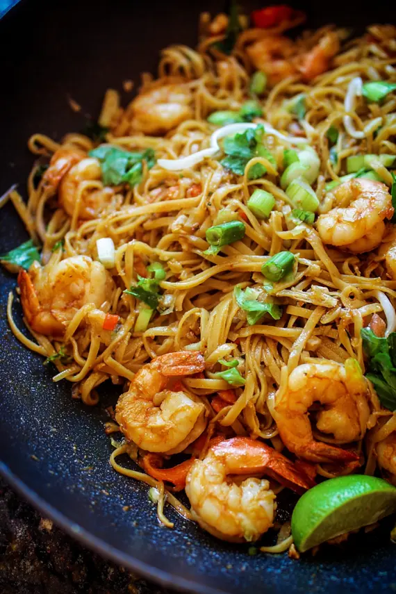 Overhead view of one pan shrimp pasta with colorful vegetables and garnishes ready to serve