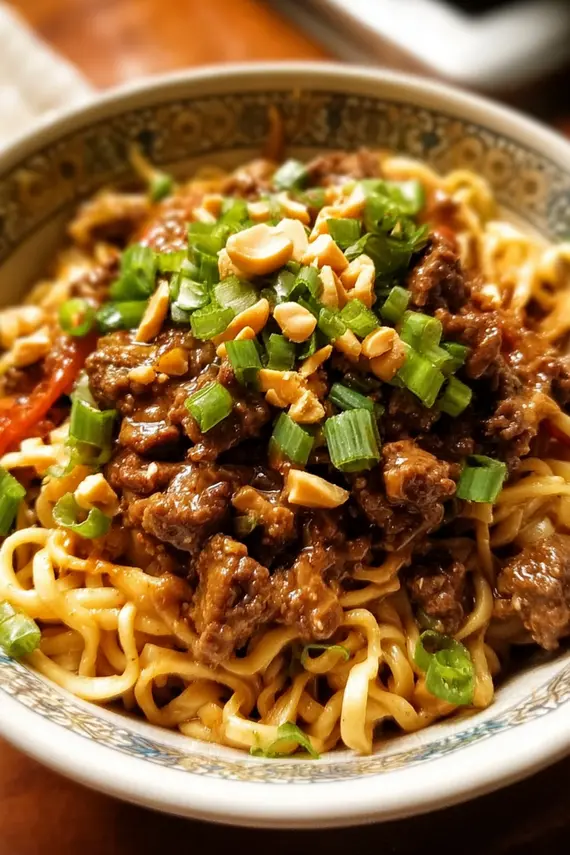 Close-up of creamy peanut sauce being drizzled over beef peanut noodles