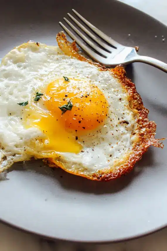 Perfect fried egg being served with toast and avocado