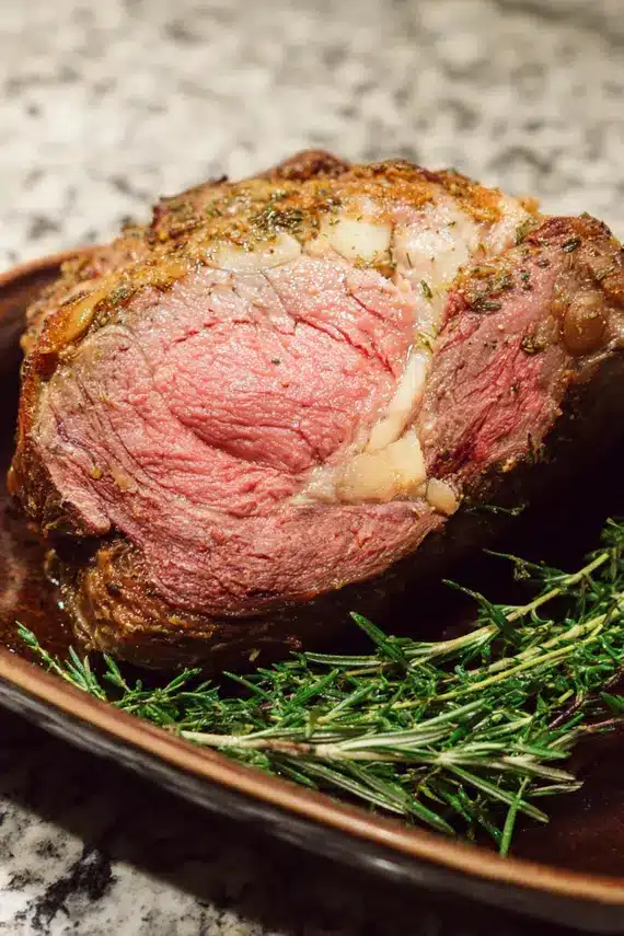 Sliced prime rib on a serving platter with roasted vegetables