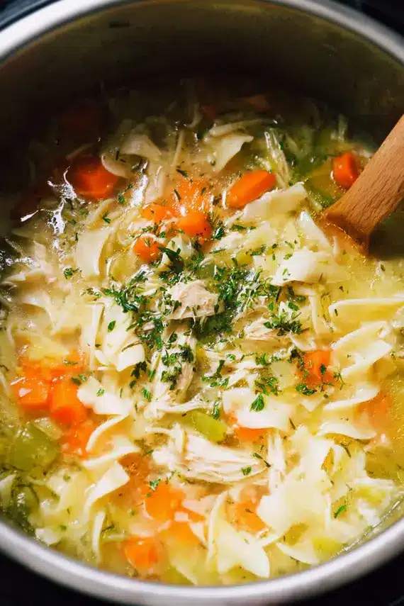 Better than grandma's instant pot chicken noodle soup in a white bowl with fresh herbs and bread on the side