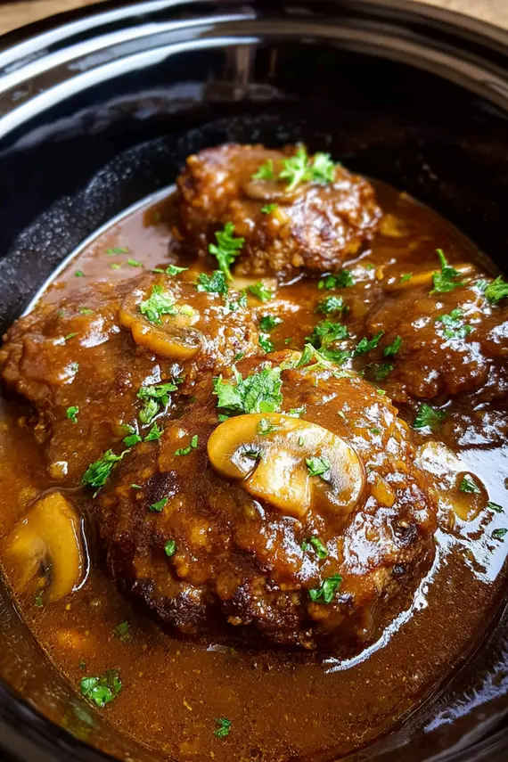 Slow Cooker Salisbury Steak with rich mushroom gravy being served over mashed potatoes