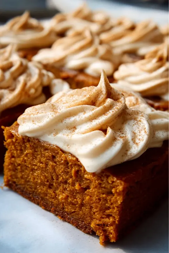 Sliced pumpkin sheet cake with cream cheese frosting on a serving platter