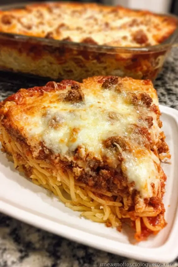 Baked spaghetti pie with golden cheese top and layers of pasta and sauce visible in a baking dish