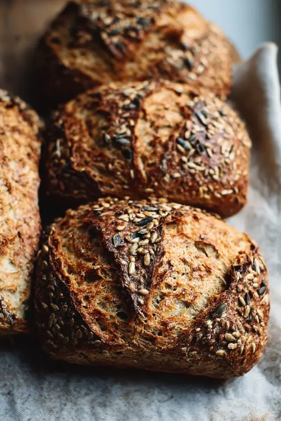 Freshly baked seeded spelt sourdough rolls on a cooling rack