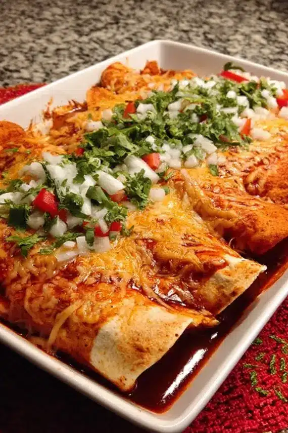 Spicy red chicken enchiladas served with rice, beans, and garnishes