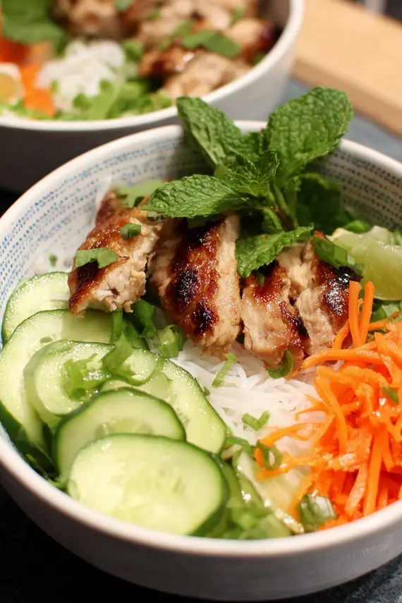 Close-up of beautifully arranged spring roll bowls with colorful vegetables, herbs, and lemongrass chicken