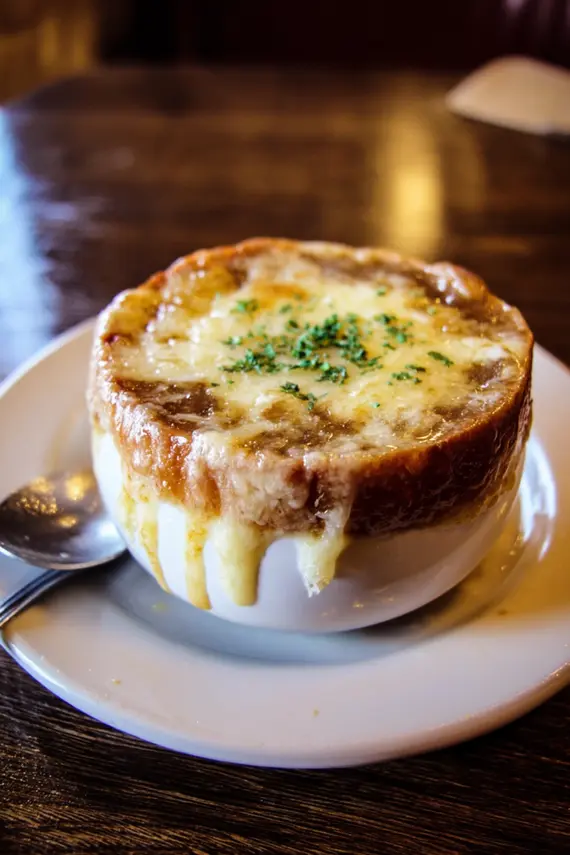 Steakhouse-style French onion soup with bubbling cheese crust in a rustic setting