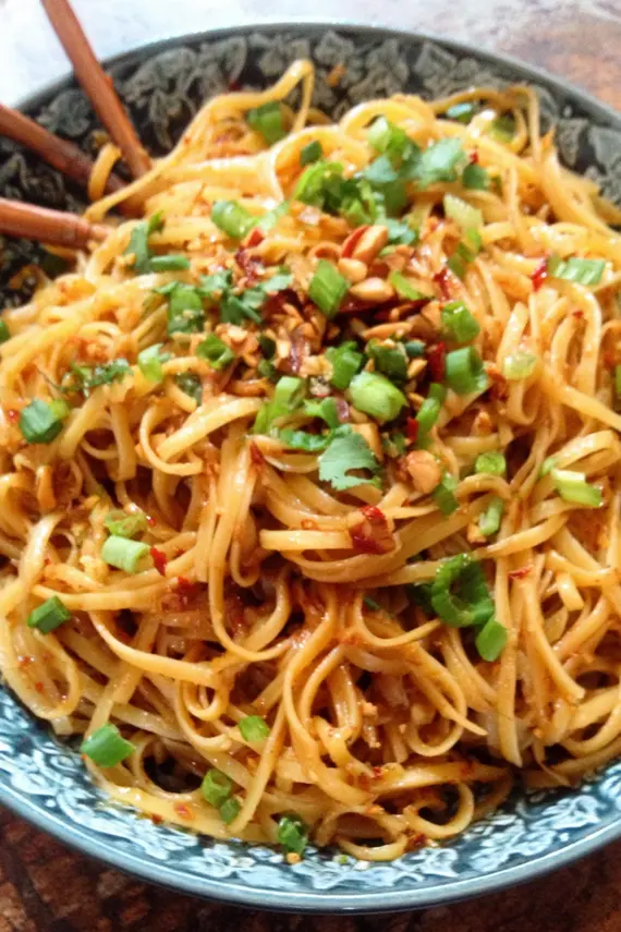 Sweet Spicy Garlic Noodles served in a bowl with chopsticks and garnished with sesame seeds
