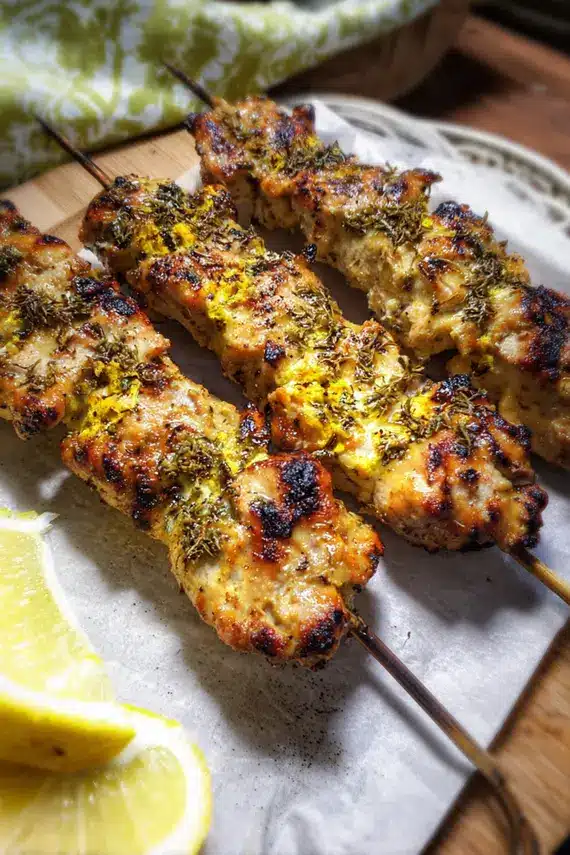 Homemade tahini sauce being drizzled over grilled chicken kebabs