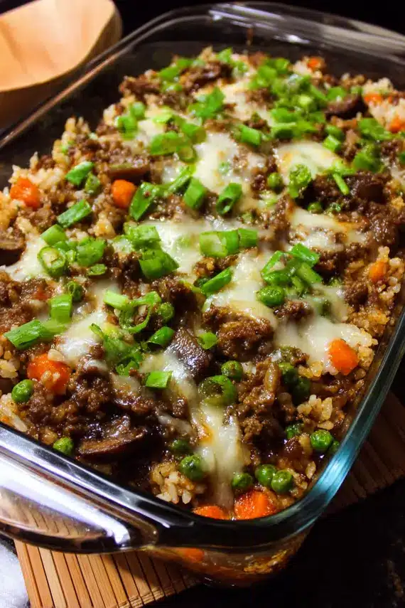 Teriyaki beef casserole with melted cheese and green onions in a ceramic baking dish