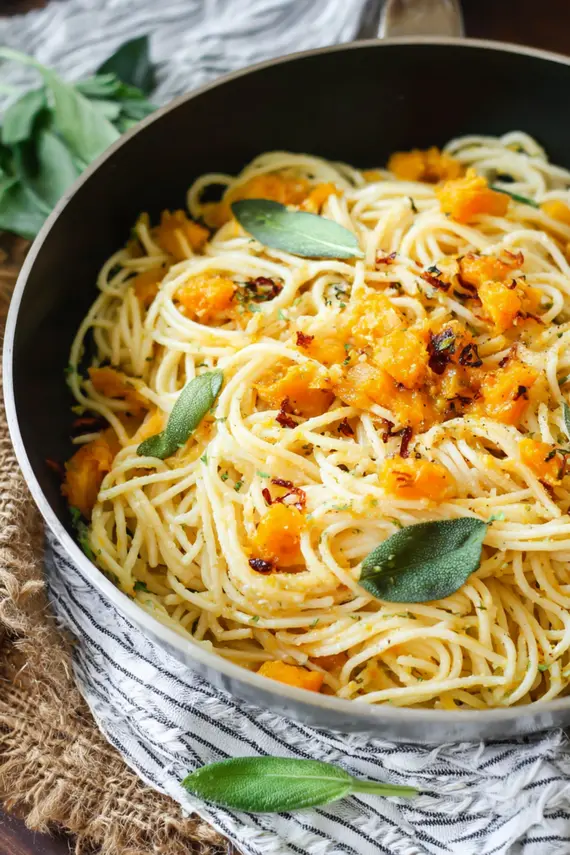 Vegetarian butternut squash pasta in a white bowl with fresh herbs