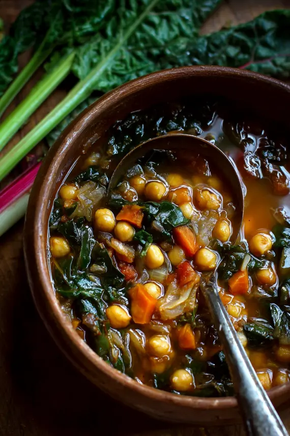 Steaming bowl of Chickpea Swiss Chard Soup topped with fresh herbs and a drizzle of olive oil