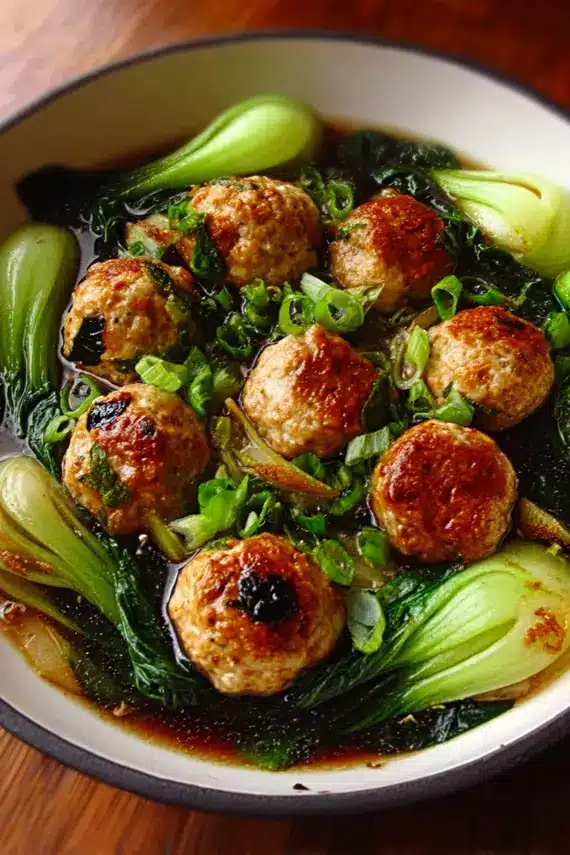 Steamed bok choy served alongside tender chicken meatballs in a traditional Asian-inspired presentation