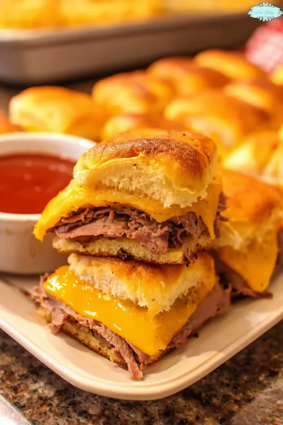 Beef cheddar sliders with melted cheese on a baking sheet