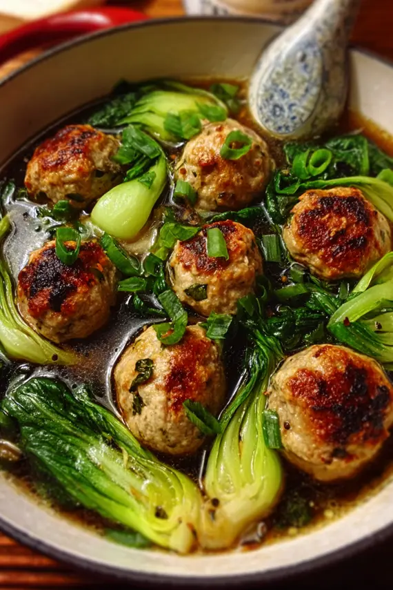 Freshly steamed chicken meatballs with tender bok choy arranged on a serving plate
