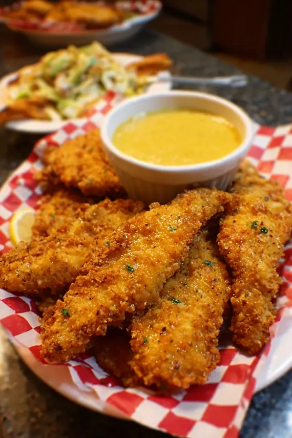 Crispy chicken tenders arranged on a serving platter with honey mustard dipping sauce
