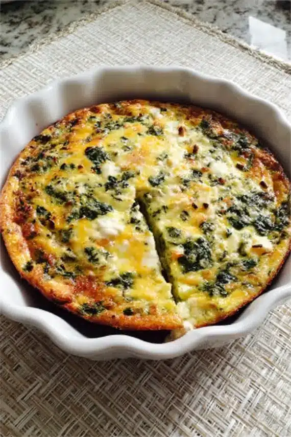 Crustless spinach quiche served on a plate with side salad and fresh herbs garnish