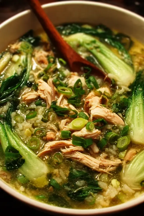 Steaming bowl of ginger chicken rice soup with bok choy showing tender chicken pieces, rice, and vibrant green bok choy leaves
