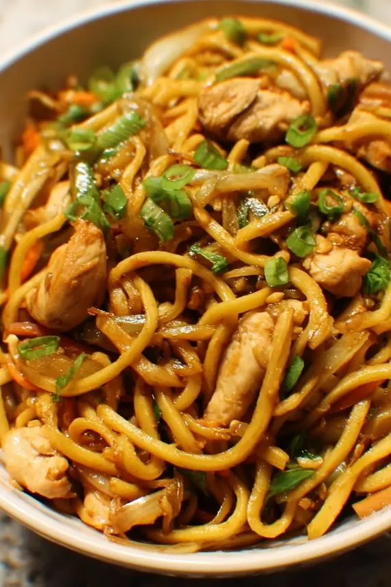 Homemade chicken lo mein in a wok with chopsticks