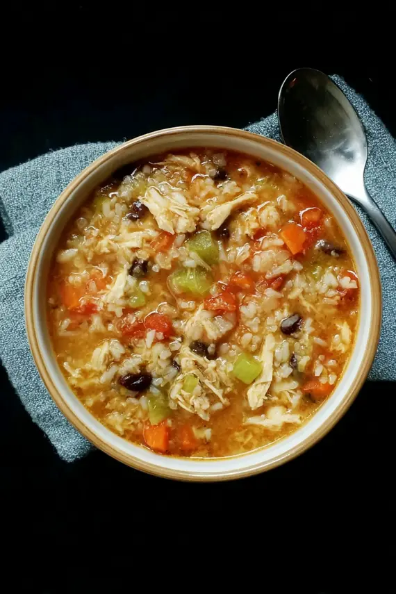 Chicken bean rice soup served in a rustic bowl with fresh herbs and crusty bread