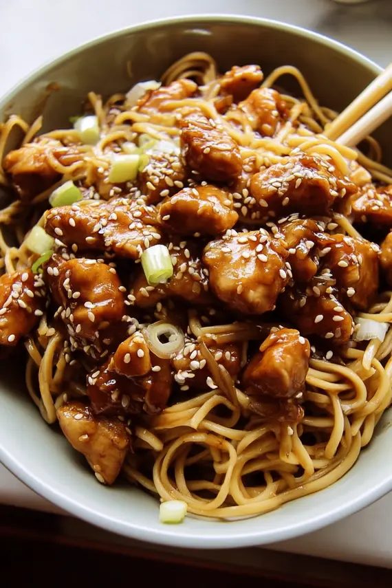 Sesame soy chicken noodles served in a bowl with chopsticks and garnish