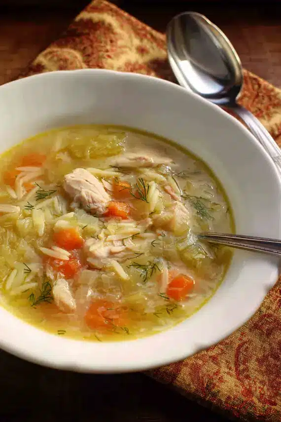 Steaming bowl of chicken fennel orzo soup with fresh herbs