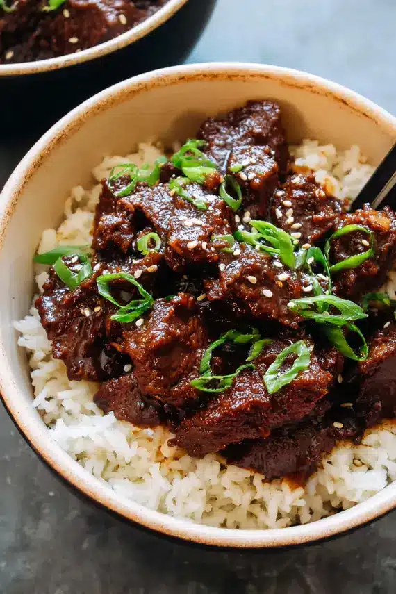 Korean slow cooker beef bites served over rice with garnishes