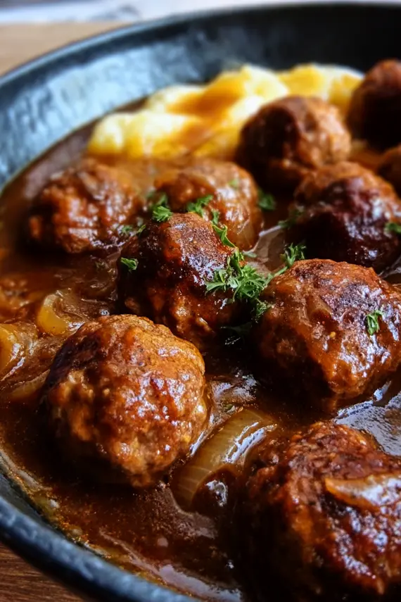 Delicious meatballs simmering in onion gravy in a skillet